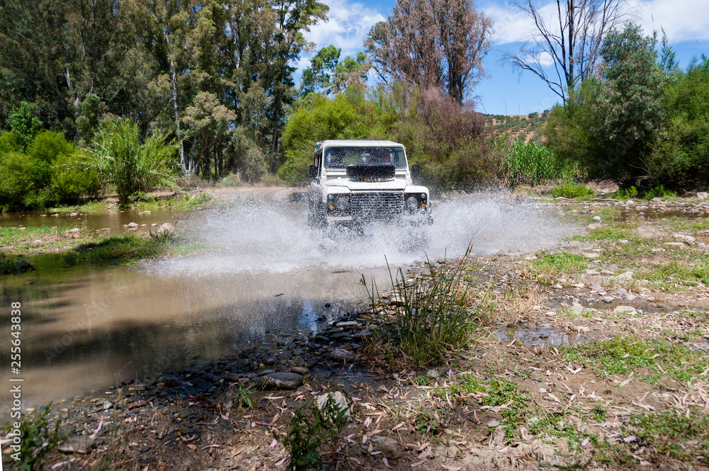Rural Andalucia. Spain. 4x4 vehicle crossing river causing water splashes. Front view.