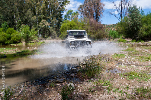 Rural Andalucia. Spain. 4x4 vehicle crossing river causing water splashes. Front view.