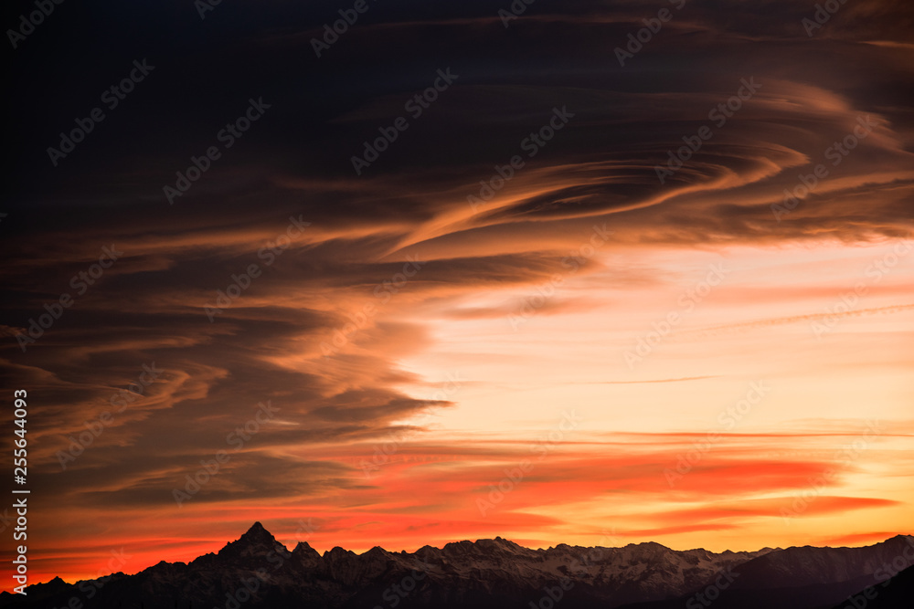 Sunset over jagged mountains with dramatic cumulus - silhouette image
