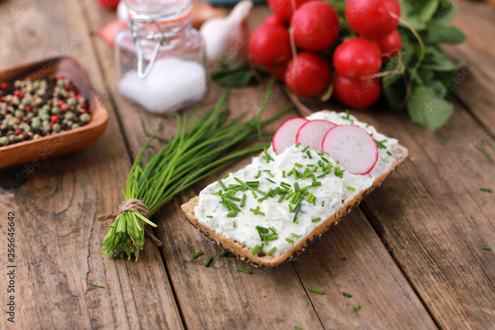 healthy breakfast - wholemeal roll with quark and fresh chive, radish on a rustic wooden table healthy breakfast - wholemeal roll with quark and fresh chive, radish on a rustic wooden table