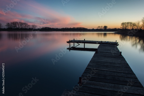 Fototapeta Naklejka Na Ścianę i Meble -  Bridge on a calm lake and pink clouds after sunset