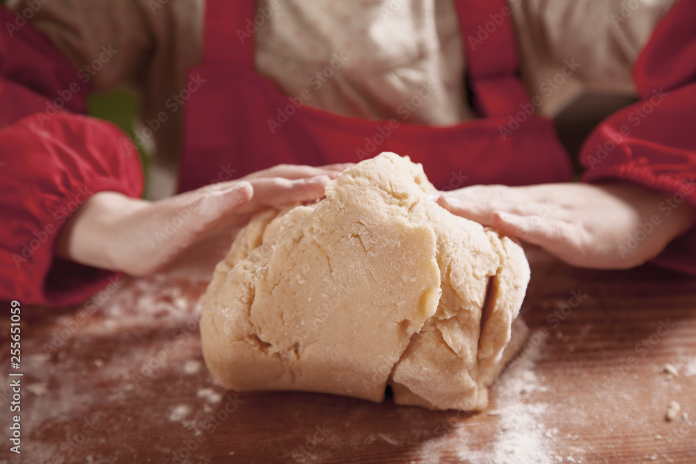 Hands of little cute child girl chef making the dough with flour on rustic wooden table. Homemade pastry for bread or pizza. Food and сooking process concept. Hands of little cute child girl chef making the dough with flour on rustic wooden table. Homemade pastry for bread or pizza. Food and сooking process concept.