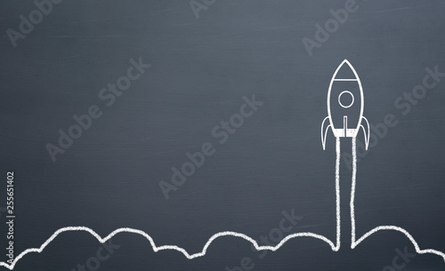 chalk drawing rocket on blackboard Going up quickly