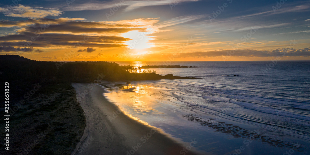Aerial view of Bastendorff Beach in Oregon near Coos Bay, with silhouetted Cape Arago Lighthouse in the background, taken during sunset