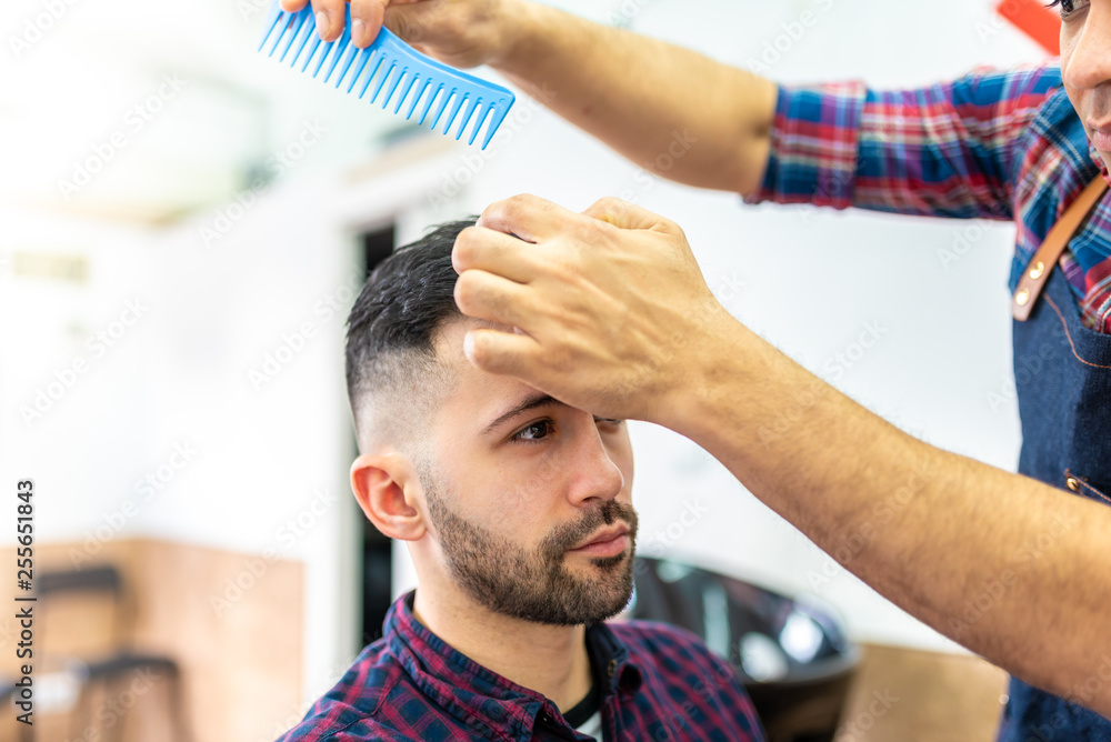 Fototapeta premium Young Man Getting a Hairstyle in a Barbershop.