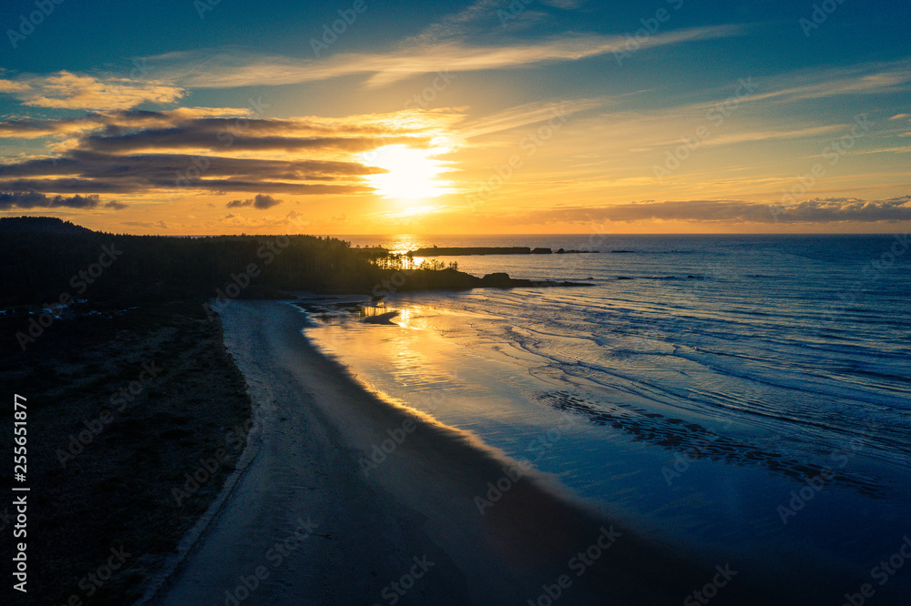 Aerial view of Bastendorff Beach in Oregon near Coos Bay, with silhouetted Cape Arago Lighthouse in the background, taken during sunset