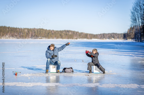 Father and son at winter fishing on frozen lake photo