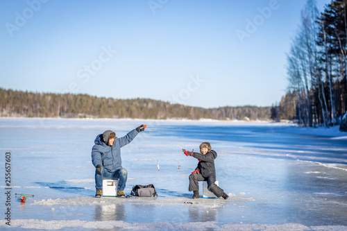Canvas Print Father and son at winter fishing on frozen lake