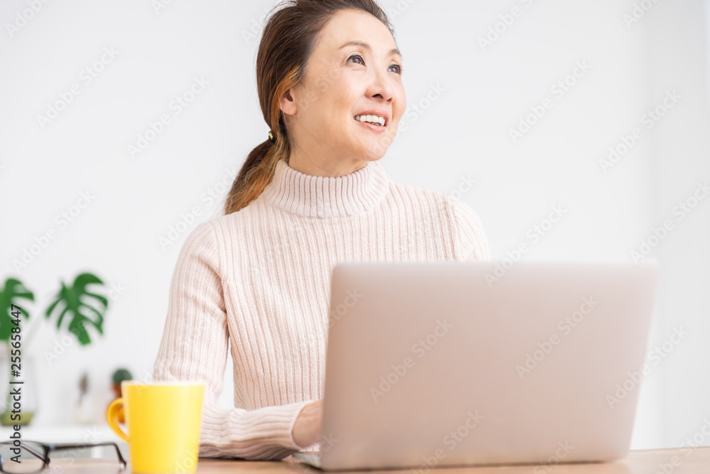 部屋でラップトップコンピューターを見るシニア女性 部屋でラップトップコンピューターを見るシニア女性