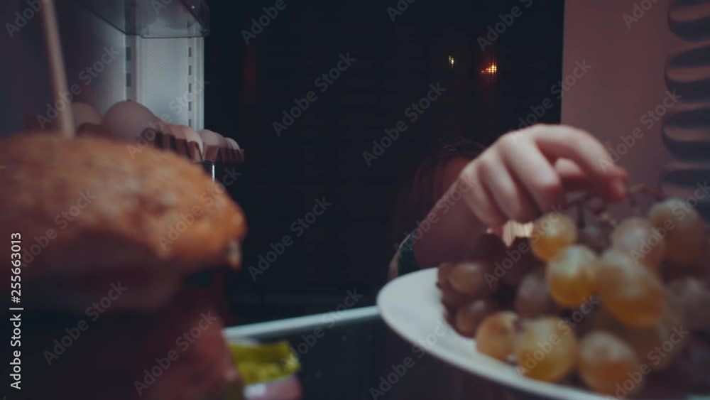 Little cute baby takes food out of the refrigerator at night, the ...