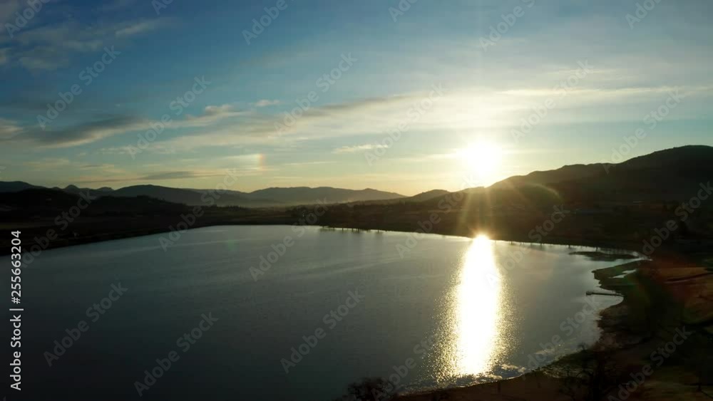 Bright Setting Sun Reflecting on Calm Blue Lake, Aerial Pull Back Bright Setting Sun Reflecting on Calm Blue Lake, Aerial Pull Back