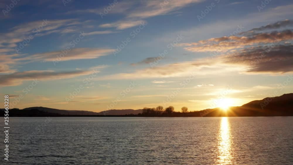 Golden Sunrise with Bright Light Rays Peaking over Lake Horizon Golden Sunrise with Bright Light Rays Peaking over Lake Horizon