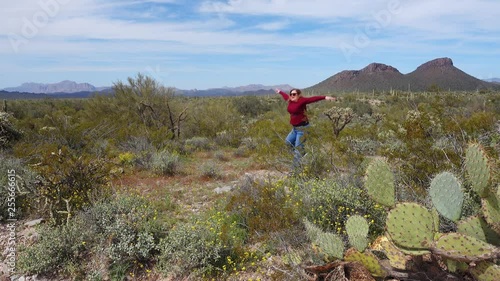 A wide shot of a woman jumping and frolicing in the Arizona desert.  	 photo