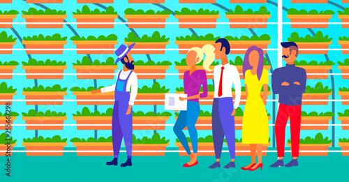 farmer in uniform with agriculture engineers group inspecting growing plants vertical farm organic hydroponic vegetables modern greenhouse interior horizontal full length