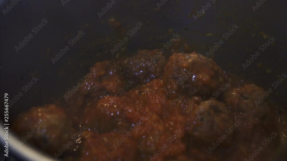 Chef hand stirring freshly prepared Meatballs in Tomato Sauce. Chef hand stirring freshly prepared Meatballs in Tomato Sauce.