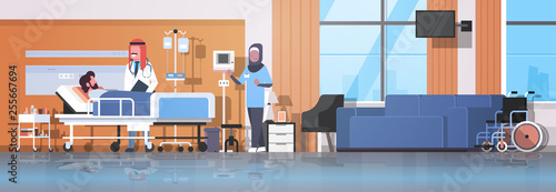 arab doctor and nurse in hijab visiting patient man lying bed with dropper intensive therapy ward healthcare concept hospital room interior medical clinic horizontal banner full length