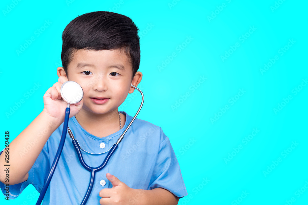 Smiling Asian kid in blue medical uniform holding stethoscope looking at camera on blue green background with copy space, healthy concept. Smiling Asian kid in blue medical uniform holding stethoscope looking at camera on blue green background with copy space, healthy concept.