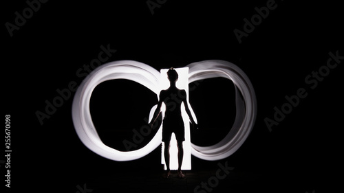 Human silhouette against white backlight in shape Infinity sign. Light painting photography. Long exposure