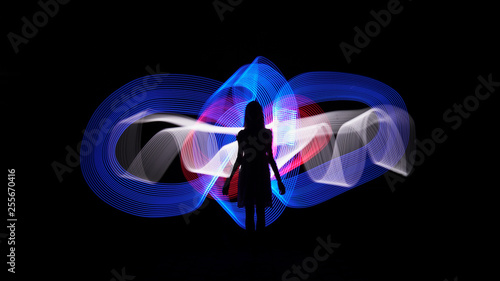 Woman silhouette against blue, white and red abstract backlight. Light painting photography. Long exposure.