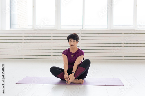 Sport, yoga, people concept - Sporty middle-aged woman practicing yoga indoors
