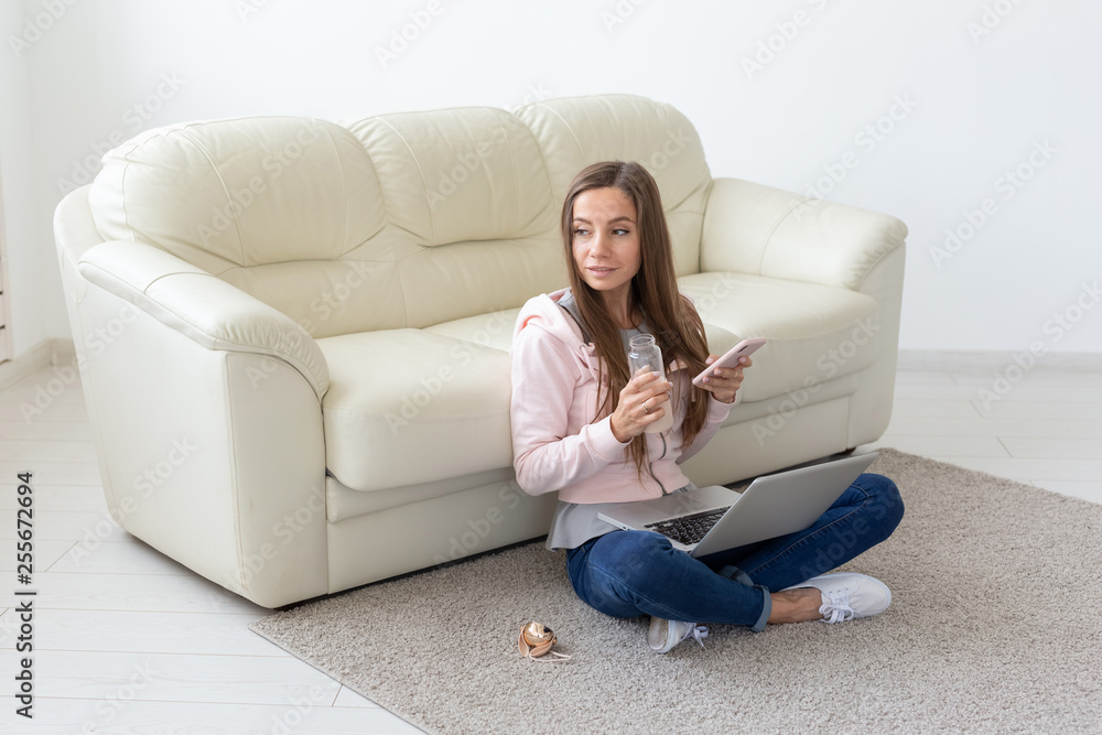 Technologies, freelance and people concept - young woman working at home, she is drinking tea on the floor, chatting in mobile Technologies, freelance and people concept - young woman working at home, she is drinking tea on the floor, chatting in mobile