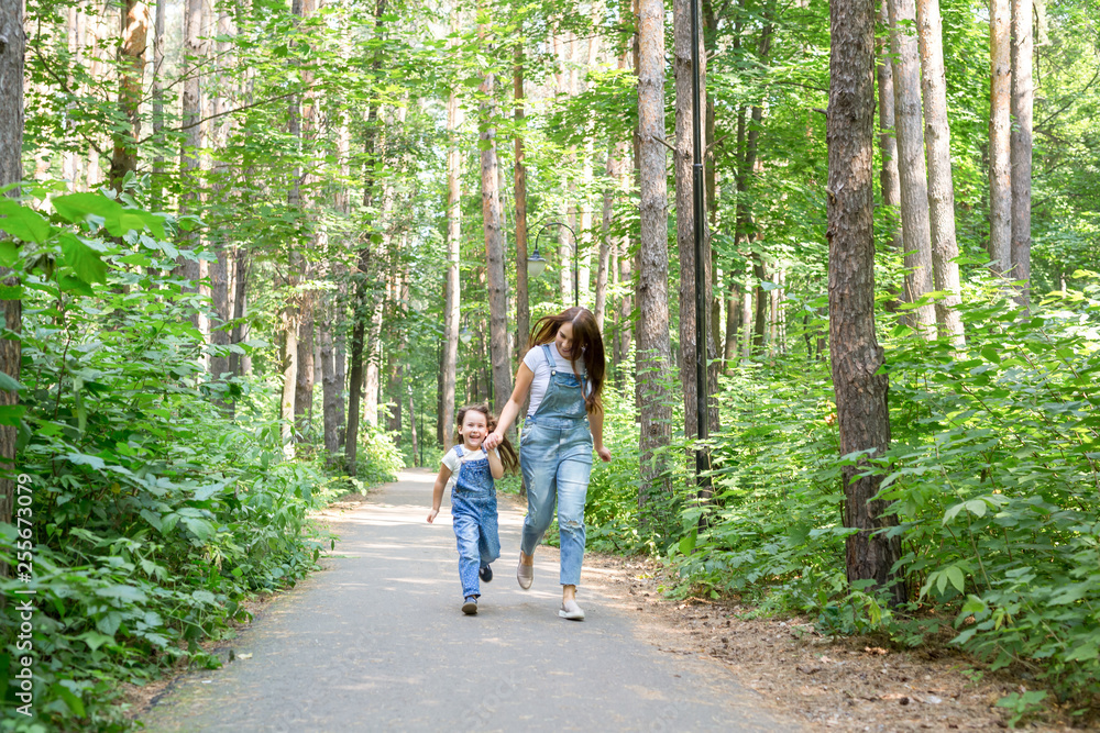 Family, nature and people concept - Mother and cute little daughter spend time together on a walk in the forest Family, nature and people concept - Mother and cute little daughter spend time together on a walk in the forest
