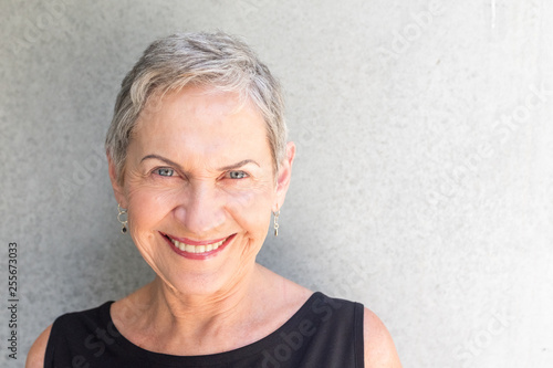 фотографія Closeup portrait of beautiful senior woman with grey hair against concrete backg