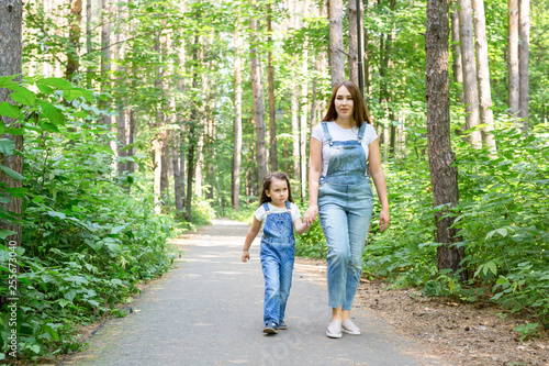 Family, nature and people concept - Mom and daughter spend time together on a walk in the green park