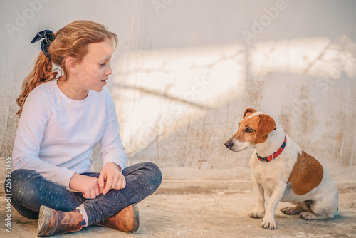 Fotografía Young girl playing with pet dog jack russell terrier outdoor.