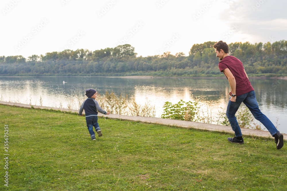 Parenthood and children concept - Father playing with a little son, trying to catch him