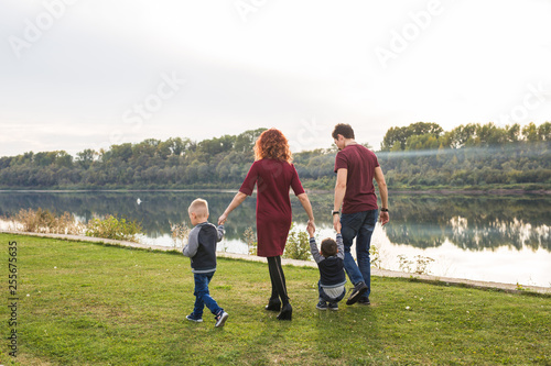 Parent, childhood and nature concept - Family playing with two sons by the water