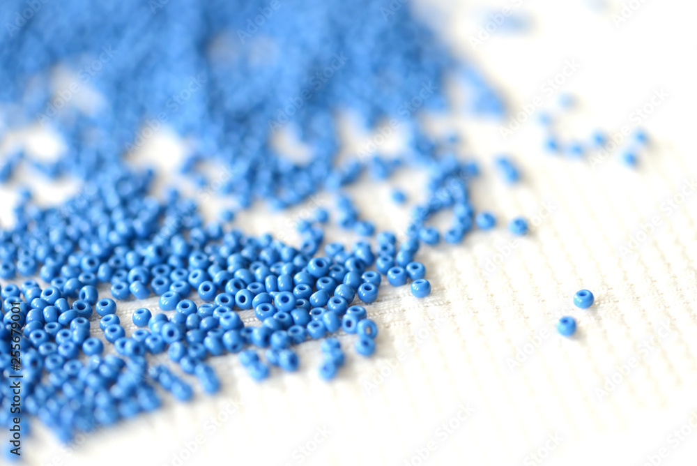 Seed beads dark blue color scattered on a textile background close up Seed beads dark blue color scattered on a textile background close up