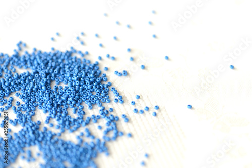 Seed beads dark blue color scattered on a textile background close up