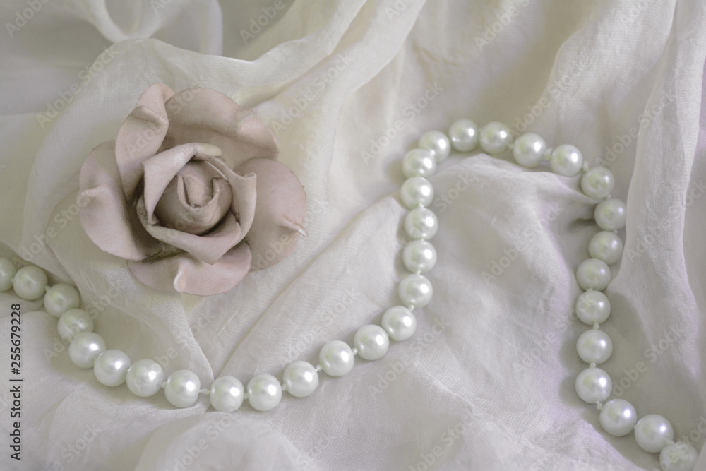 flower ash of roses on a background of translucent material and beads from pearls flower ash of roses on a background of translucent material and beads from pearls