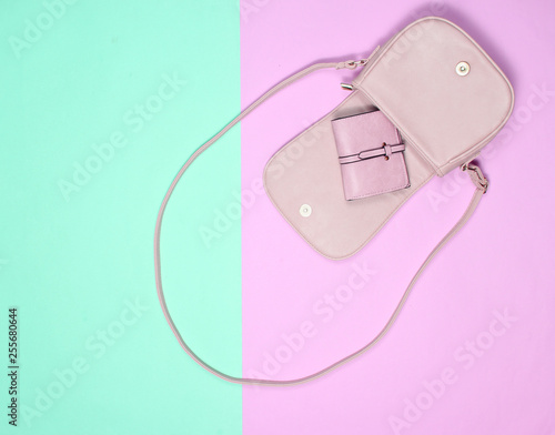 Open stylish leather bag with a purse on a pastel background. Top view, minimalism..