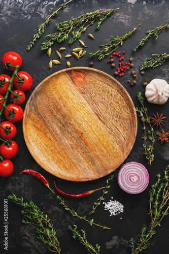 Flat lay empty wooden plate and frame of vegetables, herbs and spices. Top view, copy space. Different seasoning.