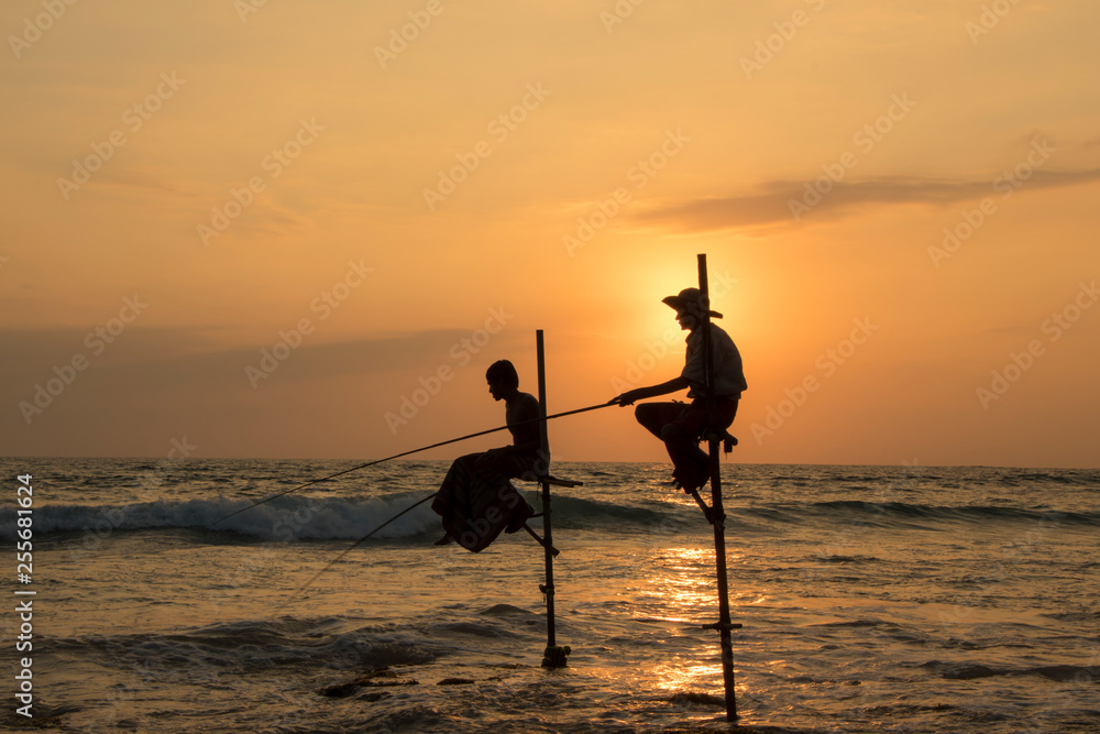 silhouette of stick fishermen on the Koggala beach at sunset Sri Lanka  Stock Photo