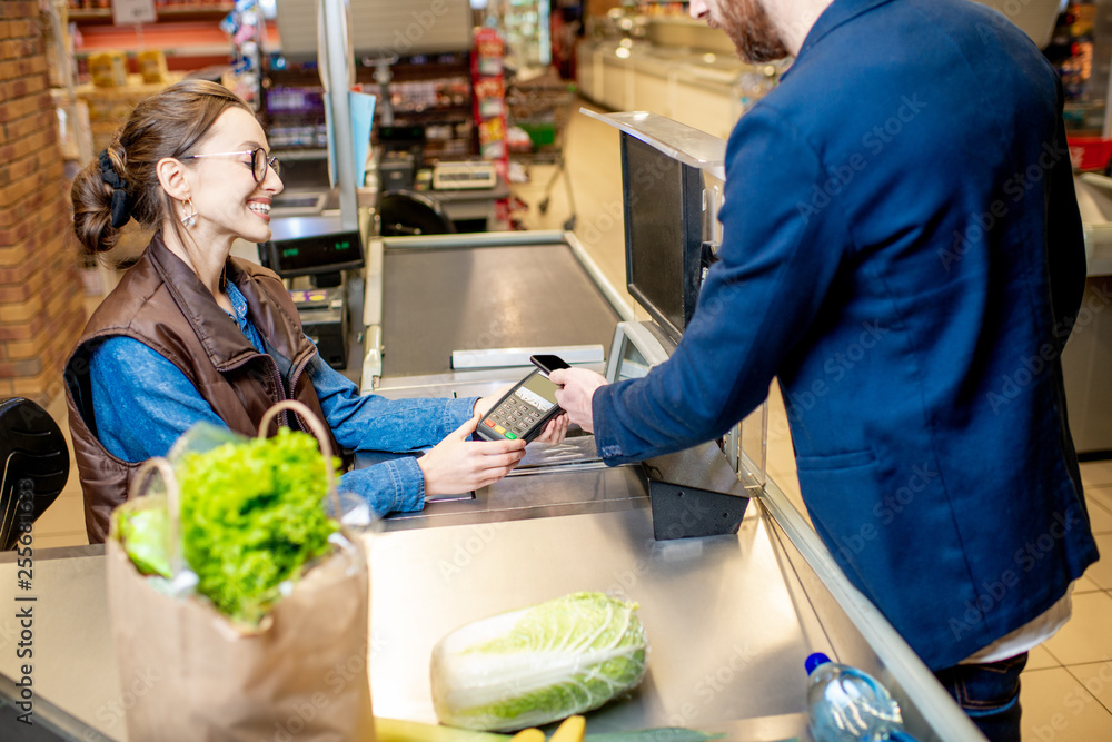 Foto de Man paying with a credit card for shopping at the cash register with cheerful cashier in