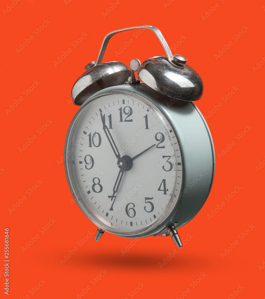 Old retro style alarm clock isolated on orange background. 6:55 am. minimalism. Photo with shadow Old retro style alarm clock isolated on orange background. 6:55 am. minimalism. Photo with shadow