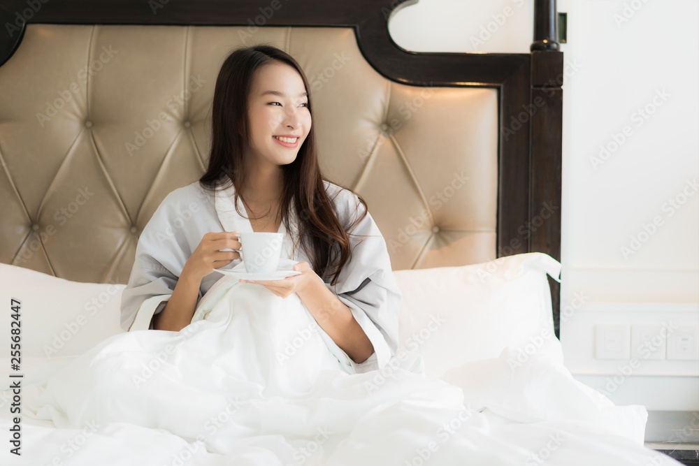 Portrait beautiful young asian woman wake up with happy smile and coffee cup on bed in bedroom interior Portrait beautiful young asian woman wake up with happy smile and coffee cup on bed in bedroom interior