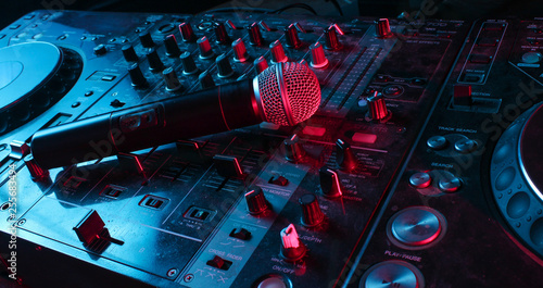 Night club, nightlife concept. Disco. Microphone on DJ remote. Neon red blue light photo