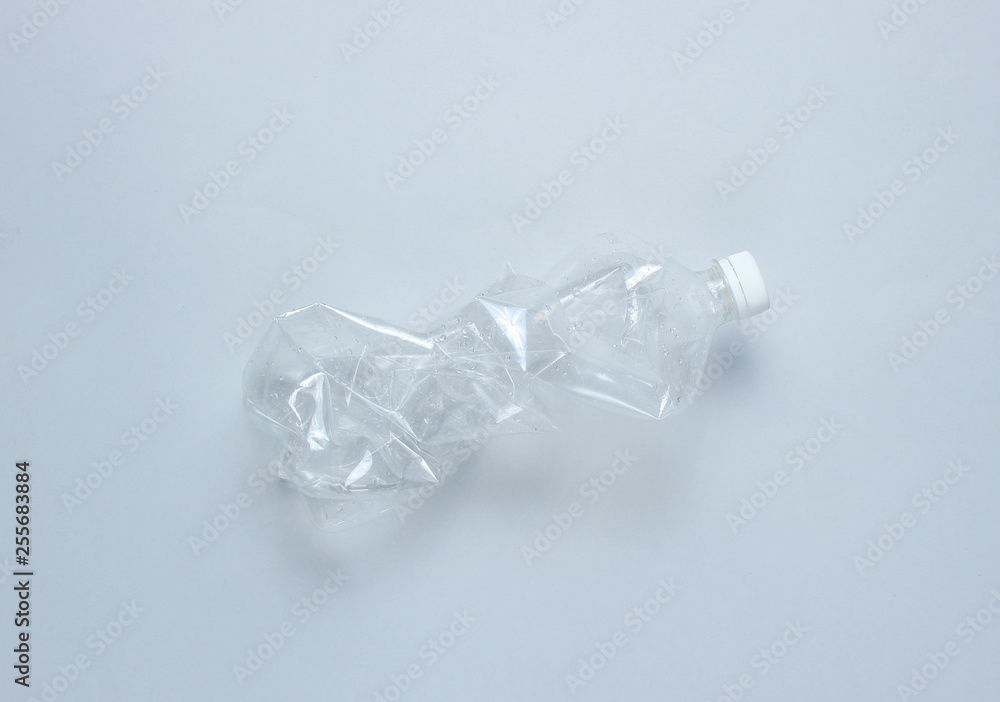 Minimalistic ecological concept. Crumpled plastic bottle on gray background. Environmental plastic pollution Minimalistic ecological concept. Crumpled plastic bottle on gray background. Environmental plastic pollution