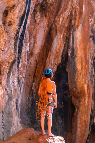 Climber in a helmet looks at a rock wall.