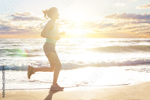 Running woman on sea beach, motion. Girl jogging on sea coast in summer sunny morning. Fitness. Healthy lifestyle.
