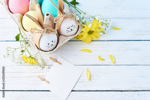 Easter colored eggs with painted faces in paper tray with decorationd on a white background photo