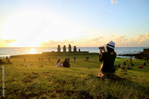 Female Tourist Taking Photos of the Famous Sunset Scene at Ahu Tahai, Easter Island, Chile  photo
