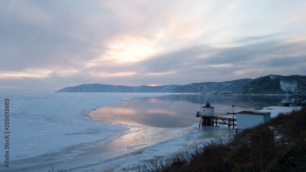 View of the pier near the village Listvyanka. The source of the Angara river from lake Baikal. Winter in Siberia. Sunset
