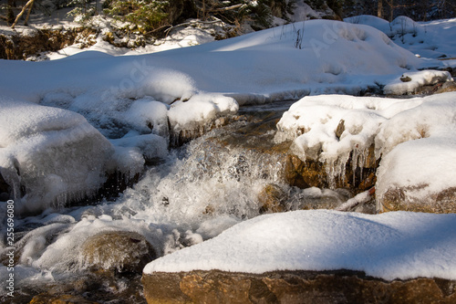 Water flowing in rapids over stone, in the winter mountains