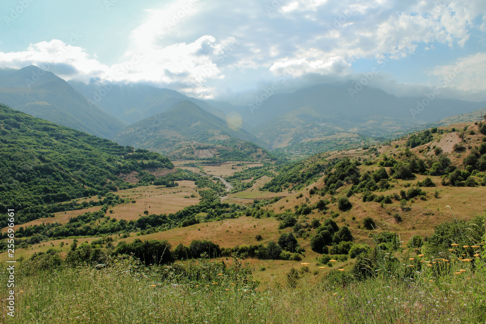 Landscape in Armenia with mountains and a valley with clouds and green brush