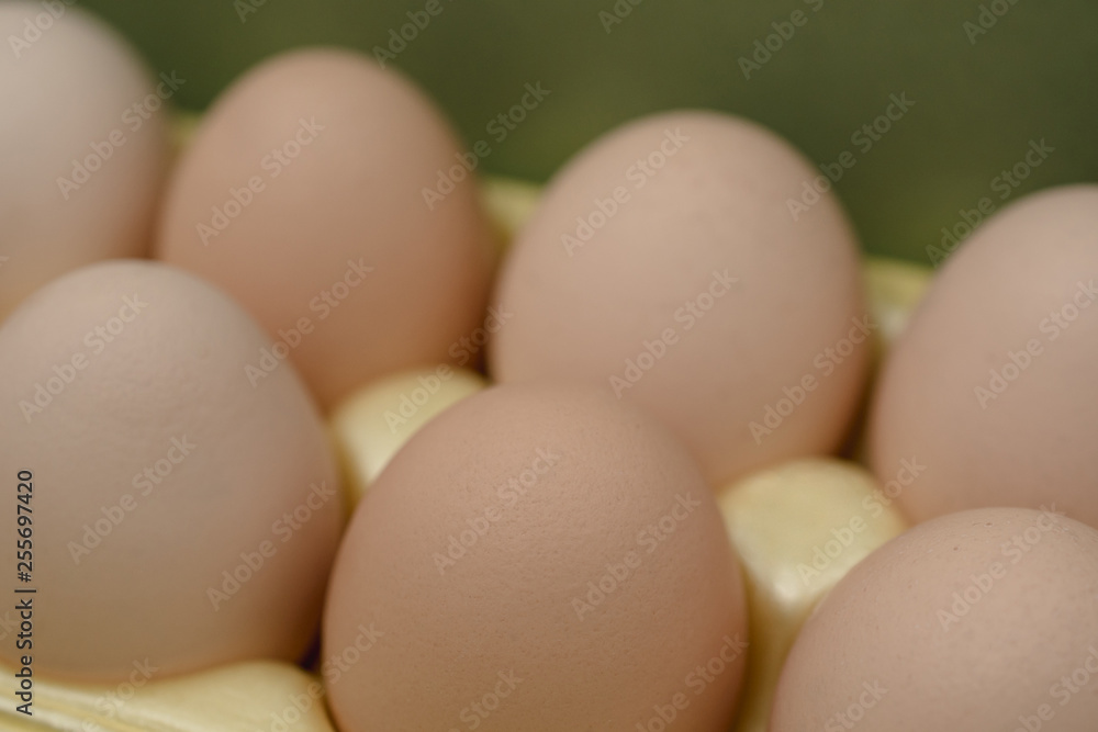 Chicken eggs lie in a yellow plastic tray.